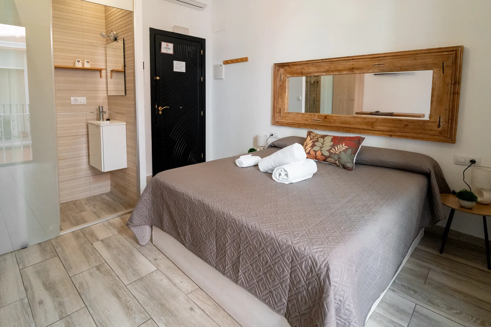Letto matrimoniale con comodini e, di lato, il bagno privato della camera doppia